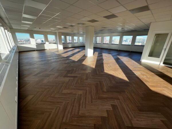 Licht en modern hoek-kantoor aan het Johanna Westerdijkplein met visgraat pvc-vloer en grote ramen met uitzicht op de stad.